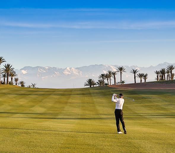 A golfer on a fairway with mountains behind