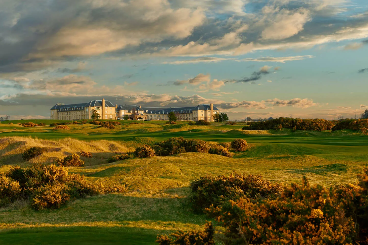 Fairmont St Andrews above gorse-lined links at sunset